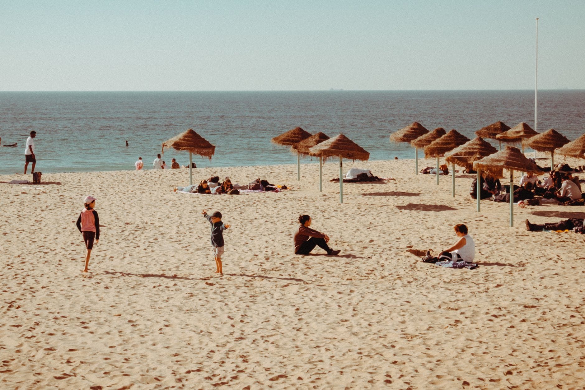 Rodziny odpoczywające pod parasolami na piaszczystej plaży latem