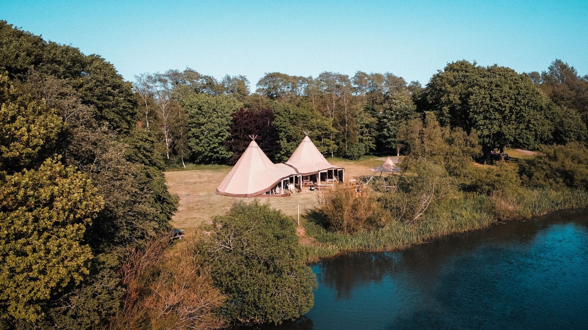 Letnie tipi nad jeziorem otoczonym lasem na Kaszubach