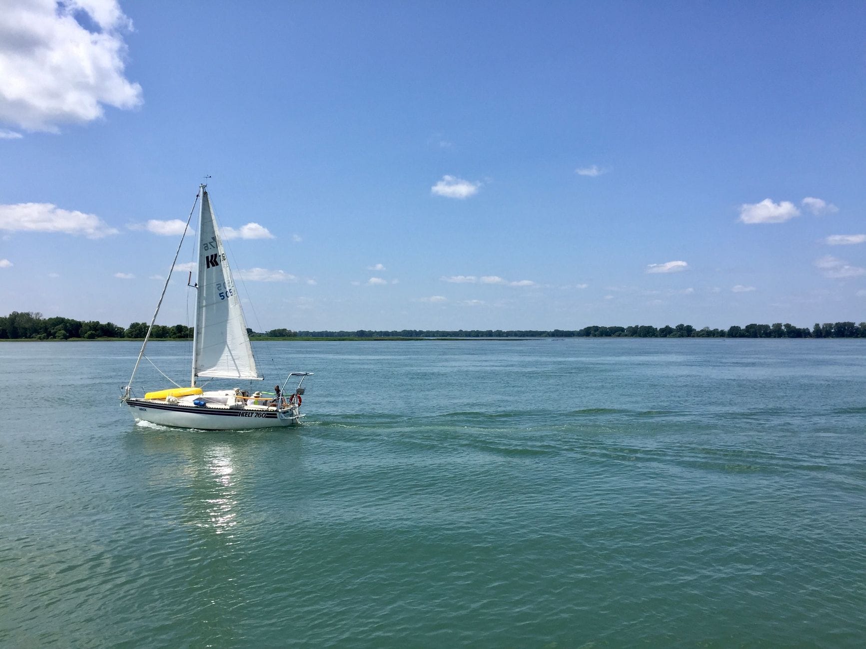 Spokojny żaglboat na jeziorze pod błękitnym niebem